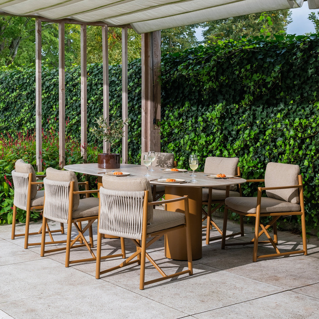 Hagemøbler som tåler å stå ute: spisegruppe med aluminiumsstoler i tau og ovalt bord under pergola